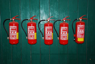 four fire extinguishers lined up against a green wall
