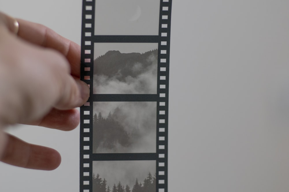 a hand holding a film strip with a mountain in the background