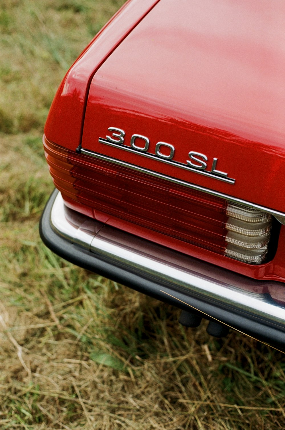 a red car parked on top of a grass covered field