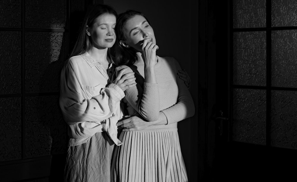 two women standing next to each other in a dark room