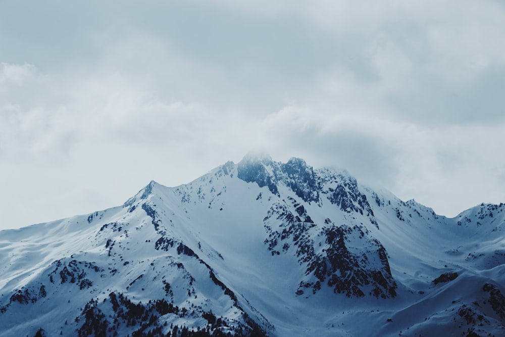 a mountain covered in snow under a cloudy sky