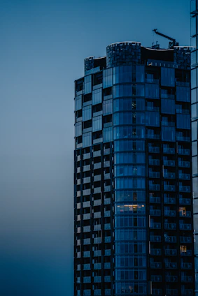 A sleek, ultramodern high-rise under construction with steel and glass elements reflecting a futuristic skyline at dusk.