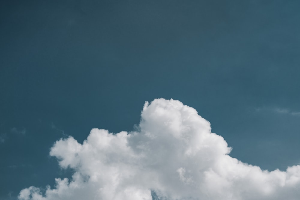 a plane flying through a cloudy blue sky