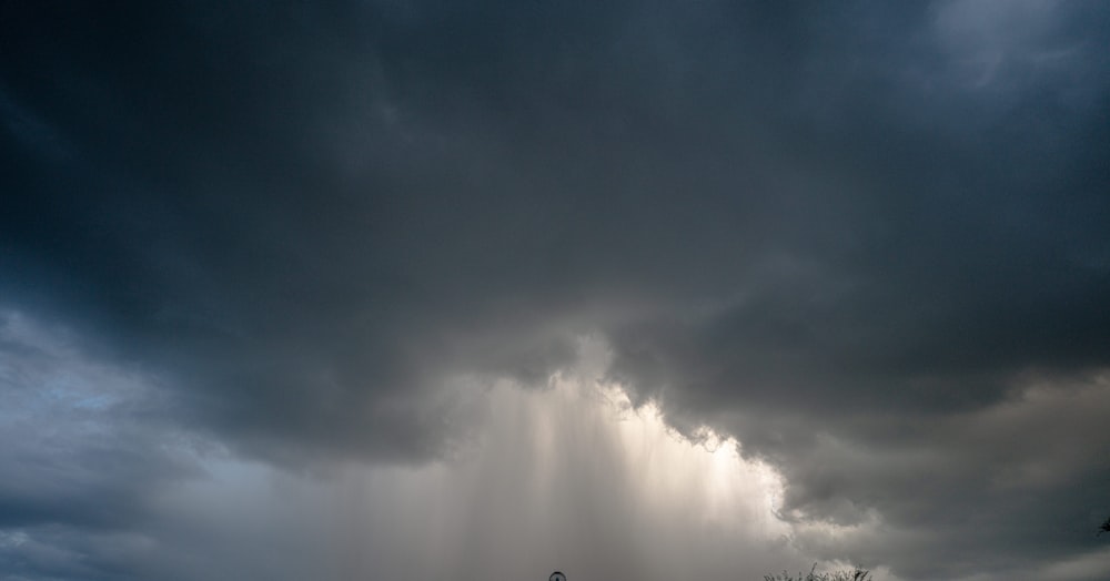 a large storm cloud looms in the sky over a field