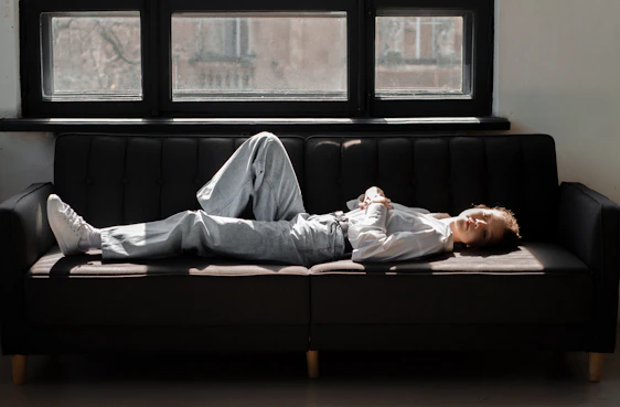 A professional cleaning technician carefully treating a sofa in a cozy living room with sunlight streaming through a window.