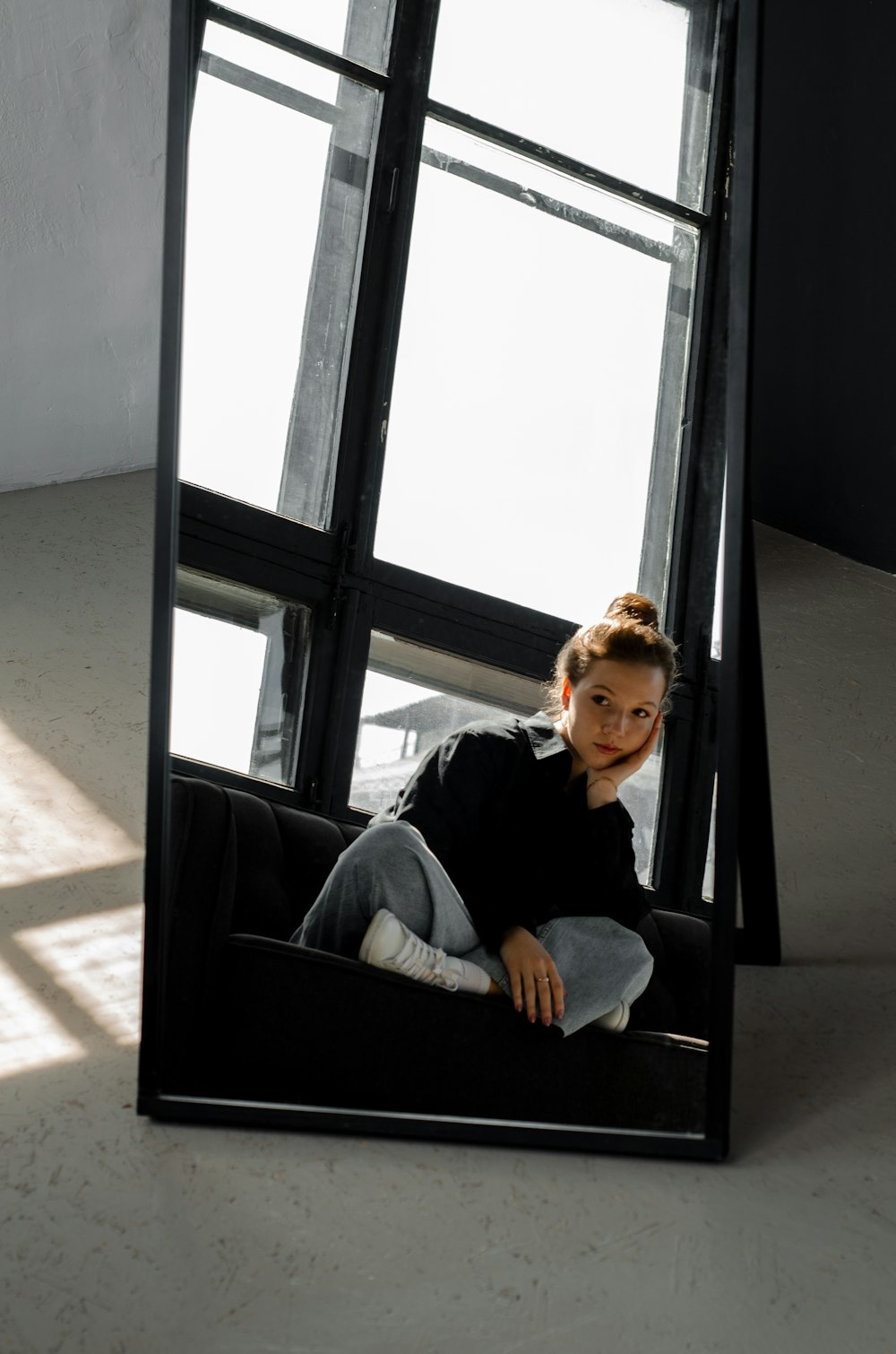 a woman sitting on a couch in front of a mirror