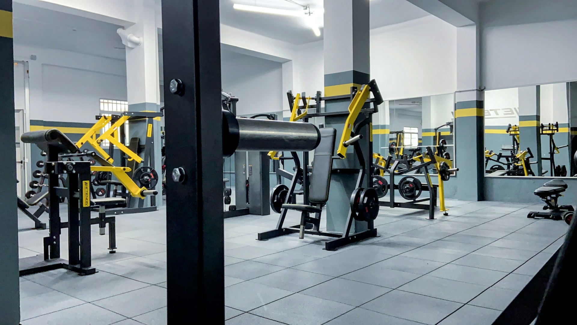 a gym with a lot of machines and mirrors