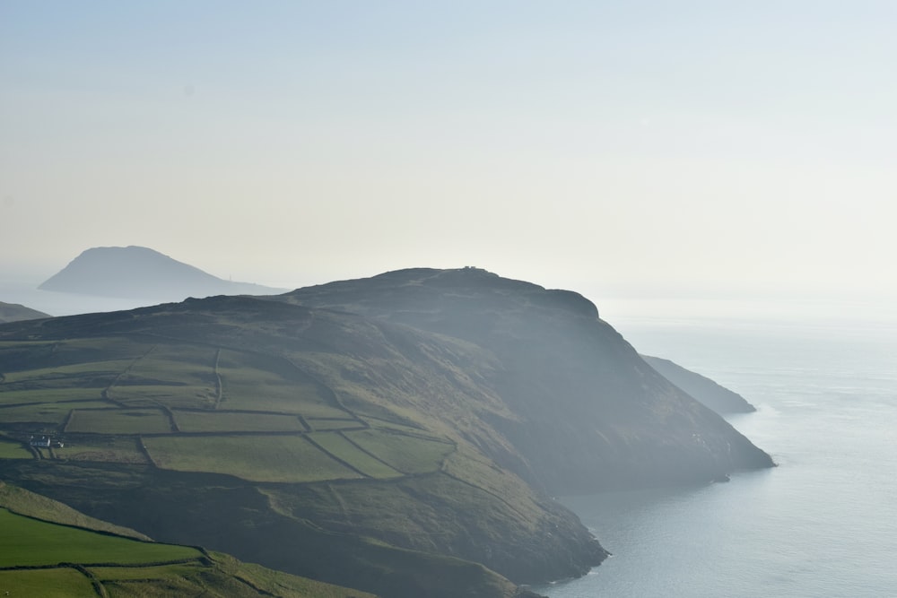 a view of a grassy hill with a body of water in the background