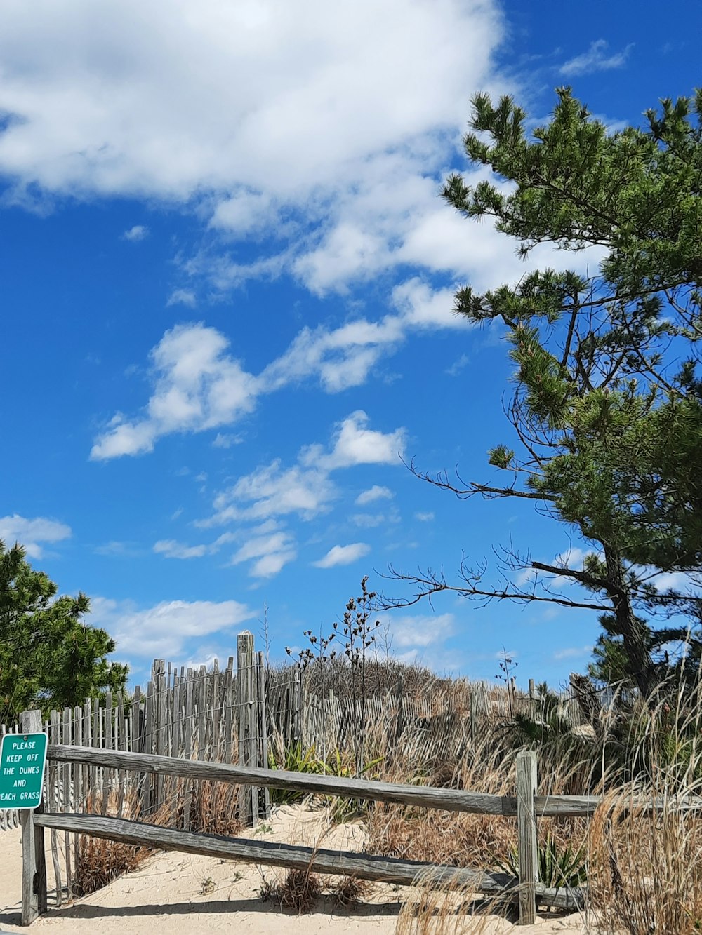 a wooden fence on a beach with a sign on it