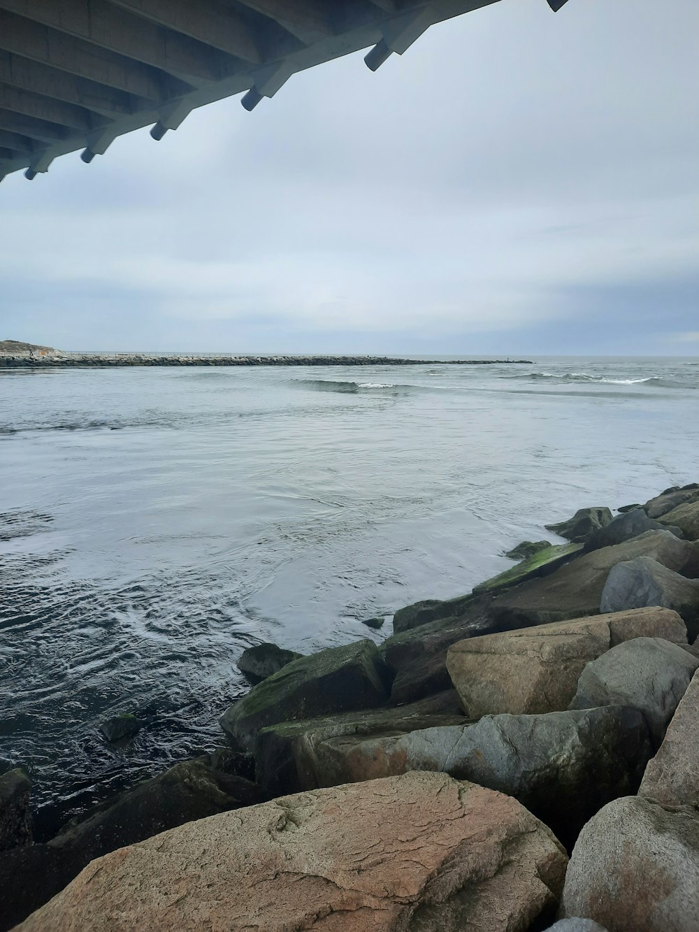 a view of a body of water from under a bridge