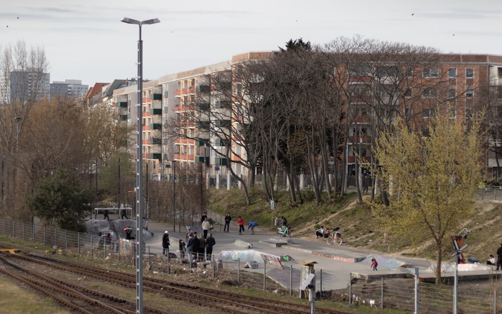 a group of people walking down a street next to a train track