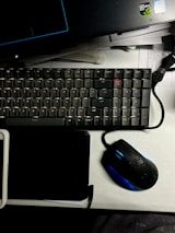 Modern gaming keyboard and mouse arranged neatly on a glass desk surface.