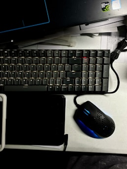 Modern gaming keyboard and mouse arranged neatly on a glass desk surface.
