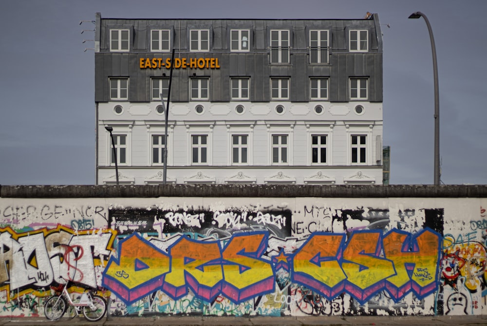 a wall covered in graffiti next to a tall building