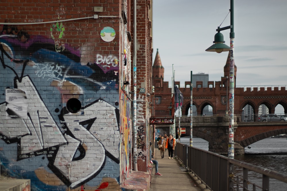 a brick wall with graffiti on it and a bridge in the background