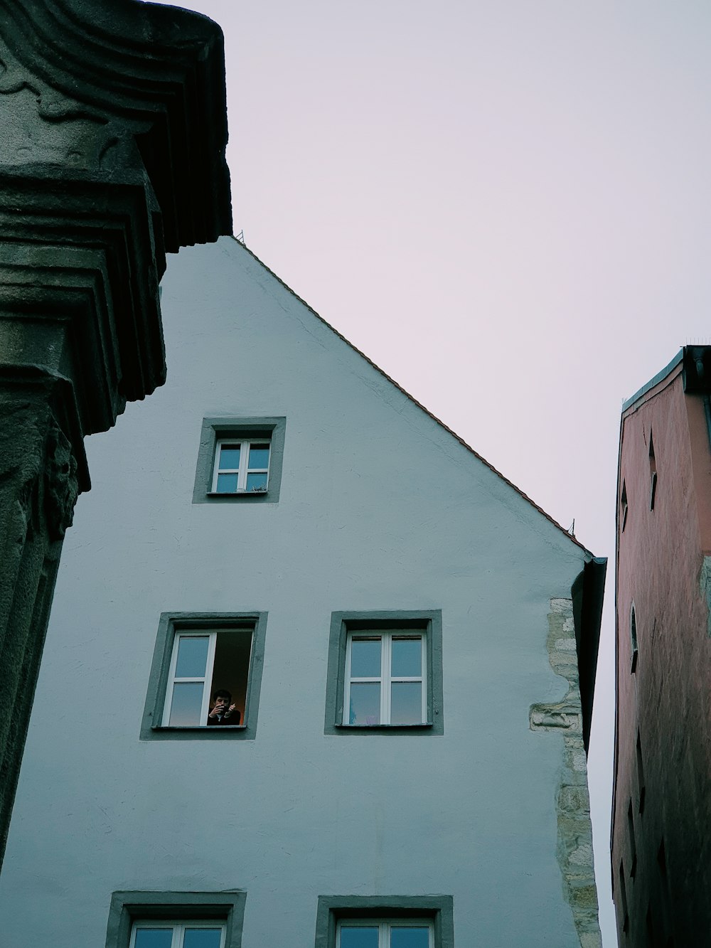 a tall white building with windows next to a tall red building