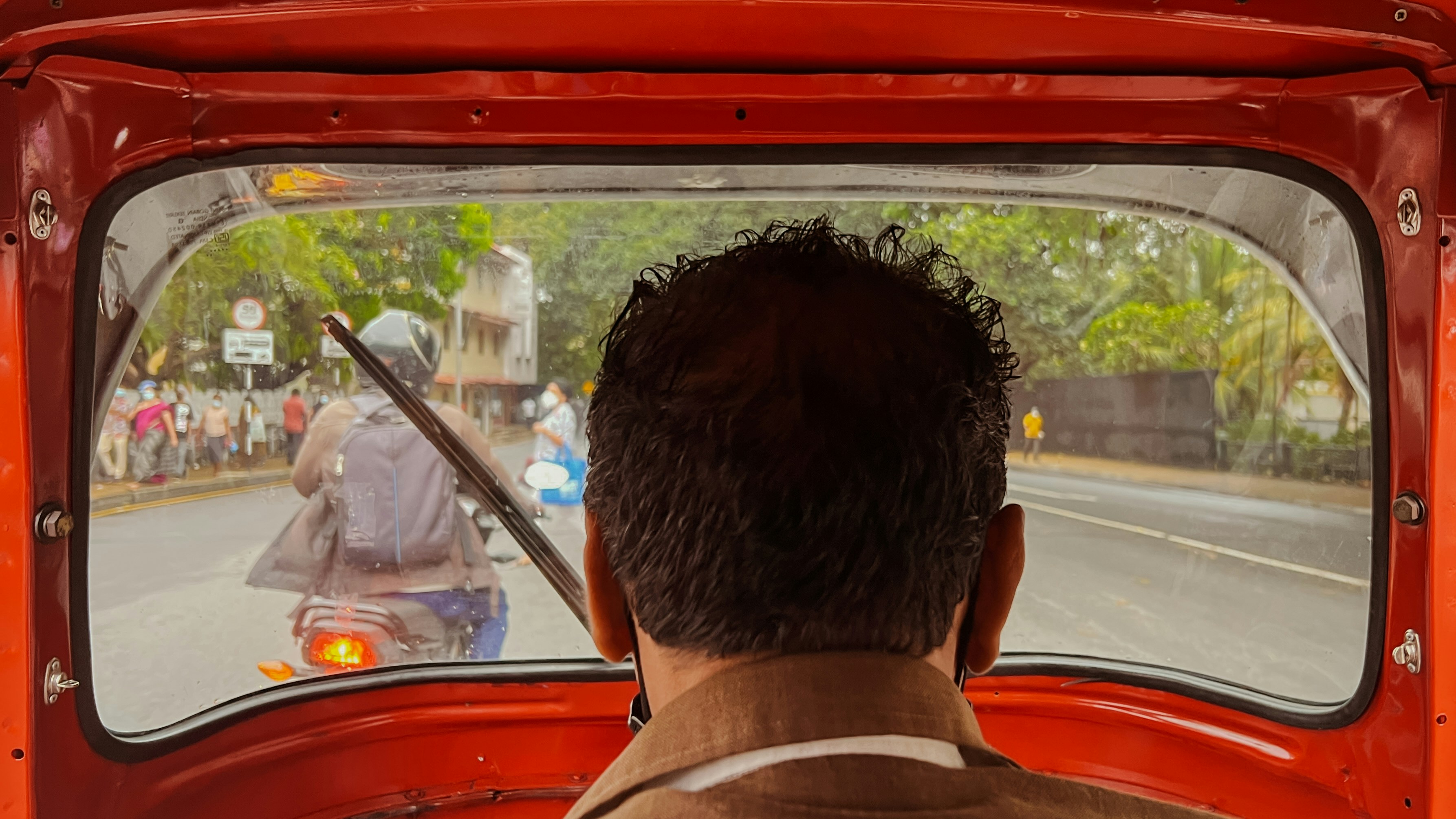 a man driving a red truck down a street
