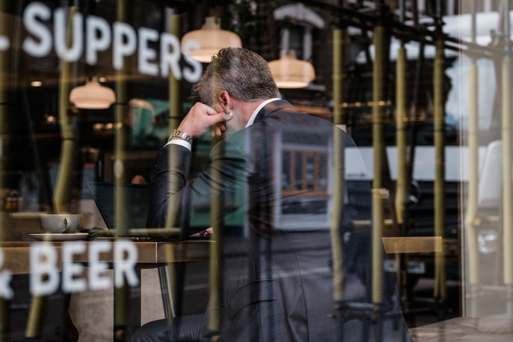 a man sitting at a table in front of a laptop computer