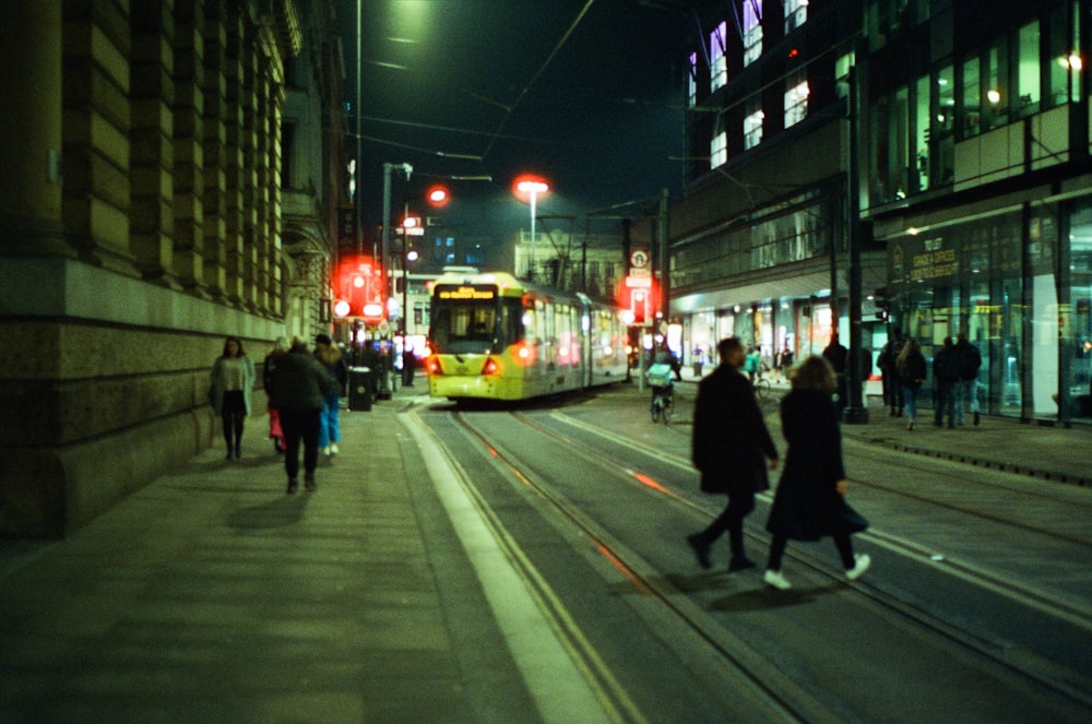 a city street at night with people walking on the sidewalk