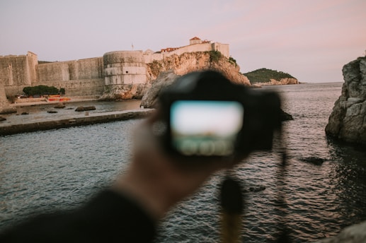 a person taking a picture of a castle by the water