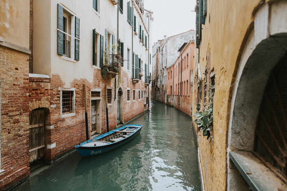 a small boat is floating down a narrow canal