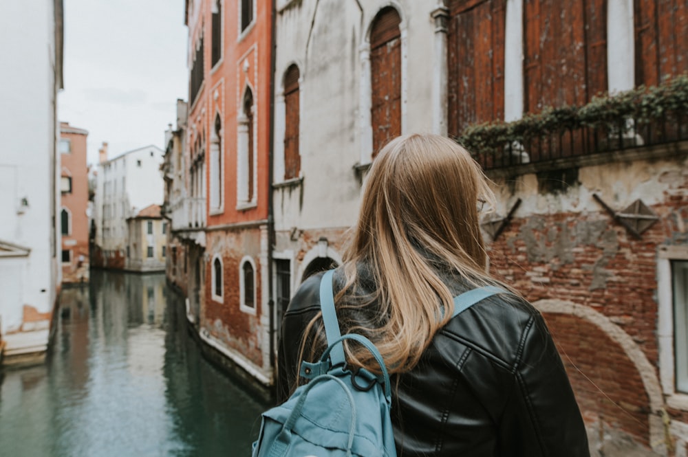 a woman with a backpack walking down a canal