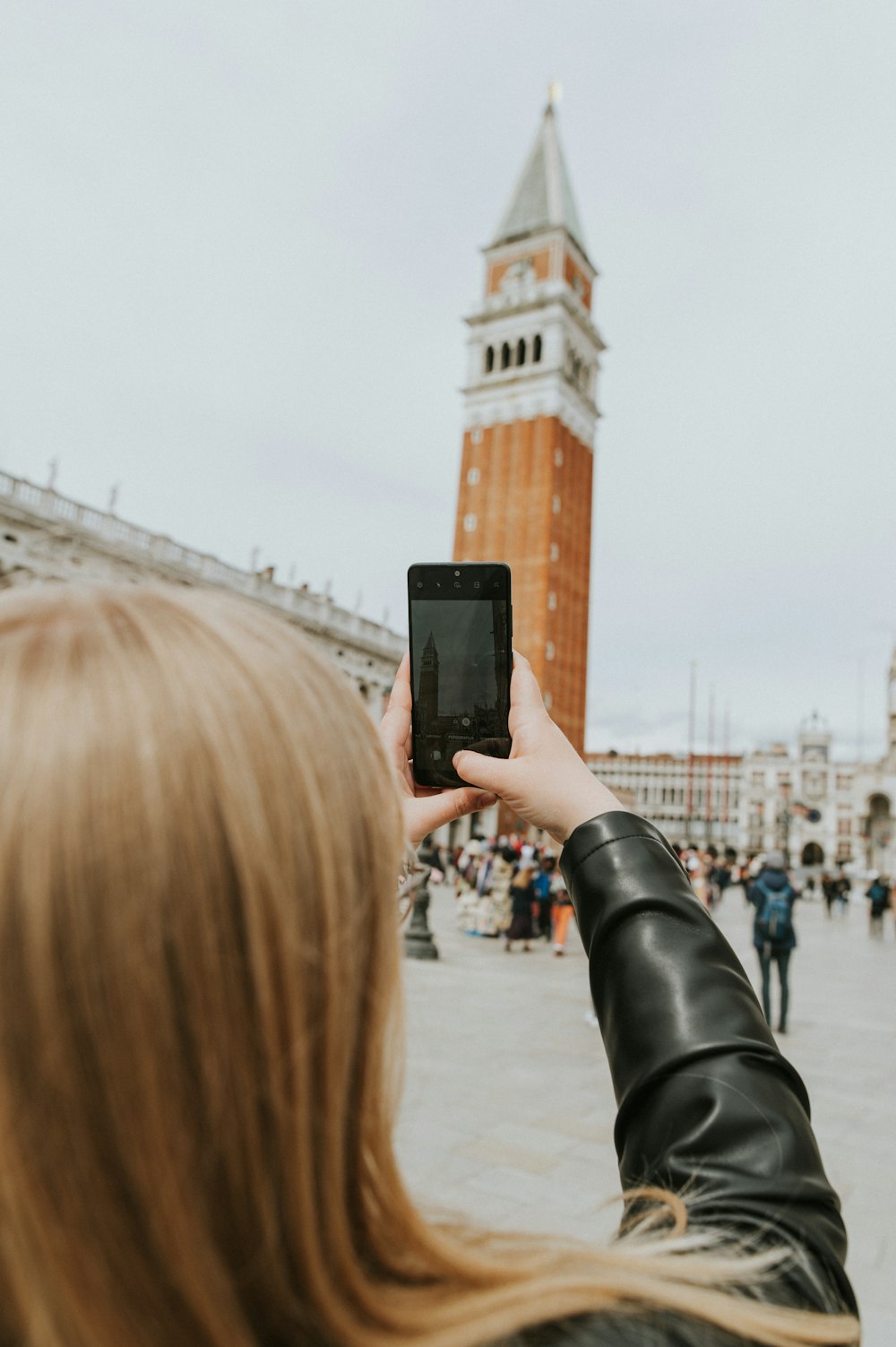 a woman taking a picture of a clock tower