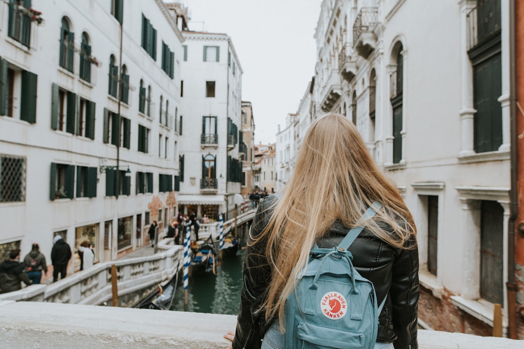 a woman with a blue backpack walking down a street,