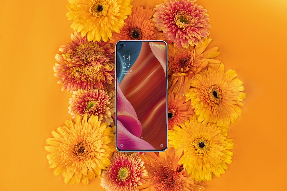 un téléphone portable entouré de fleurs sur fond orange