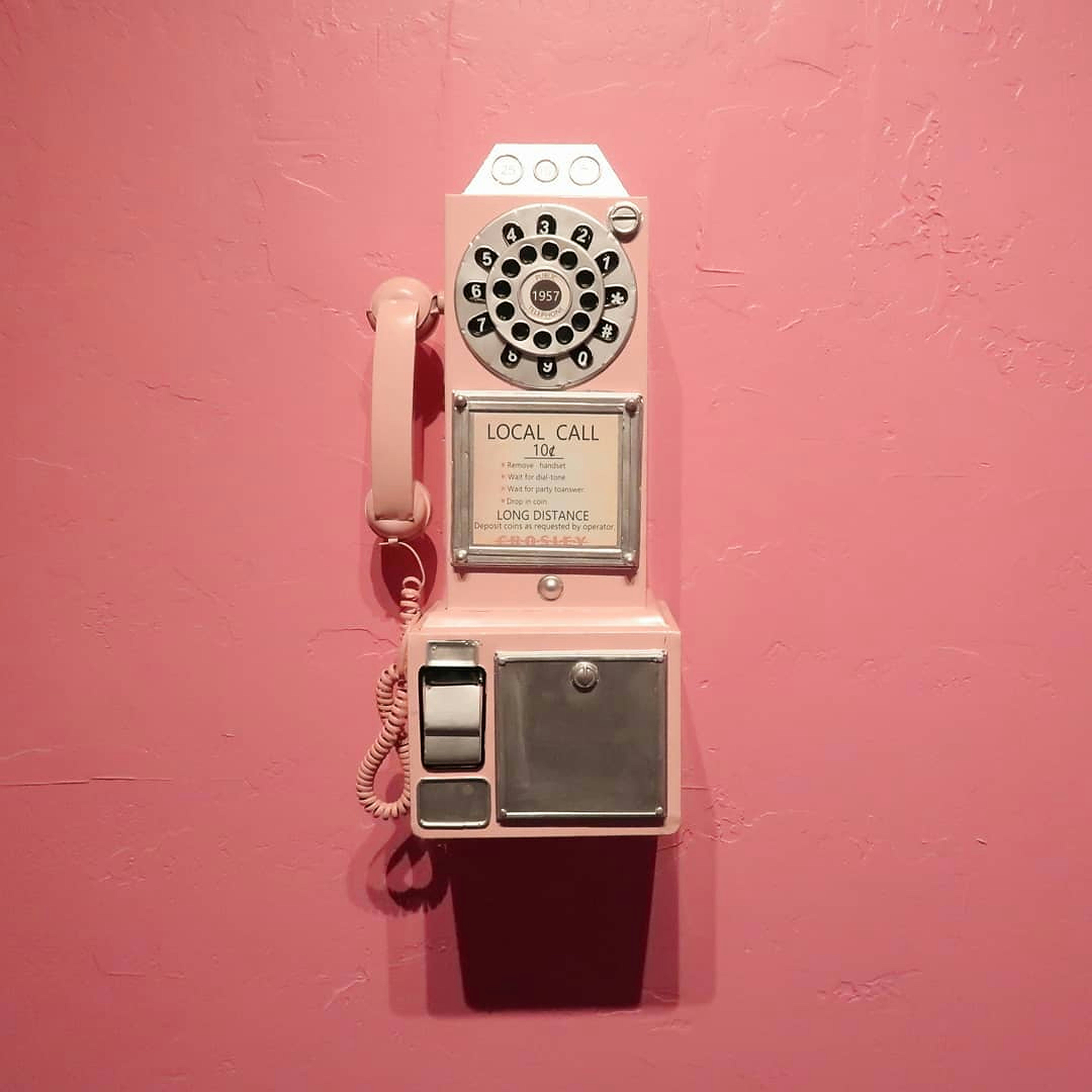 a pink wall with an old fashioned phone on it