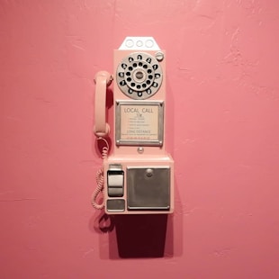 a pink wall with an old fashioned phone on it