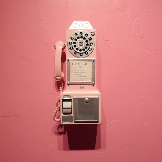 a pink wall with an old fashioned phone on it