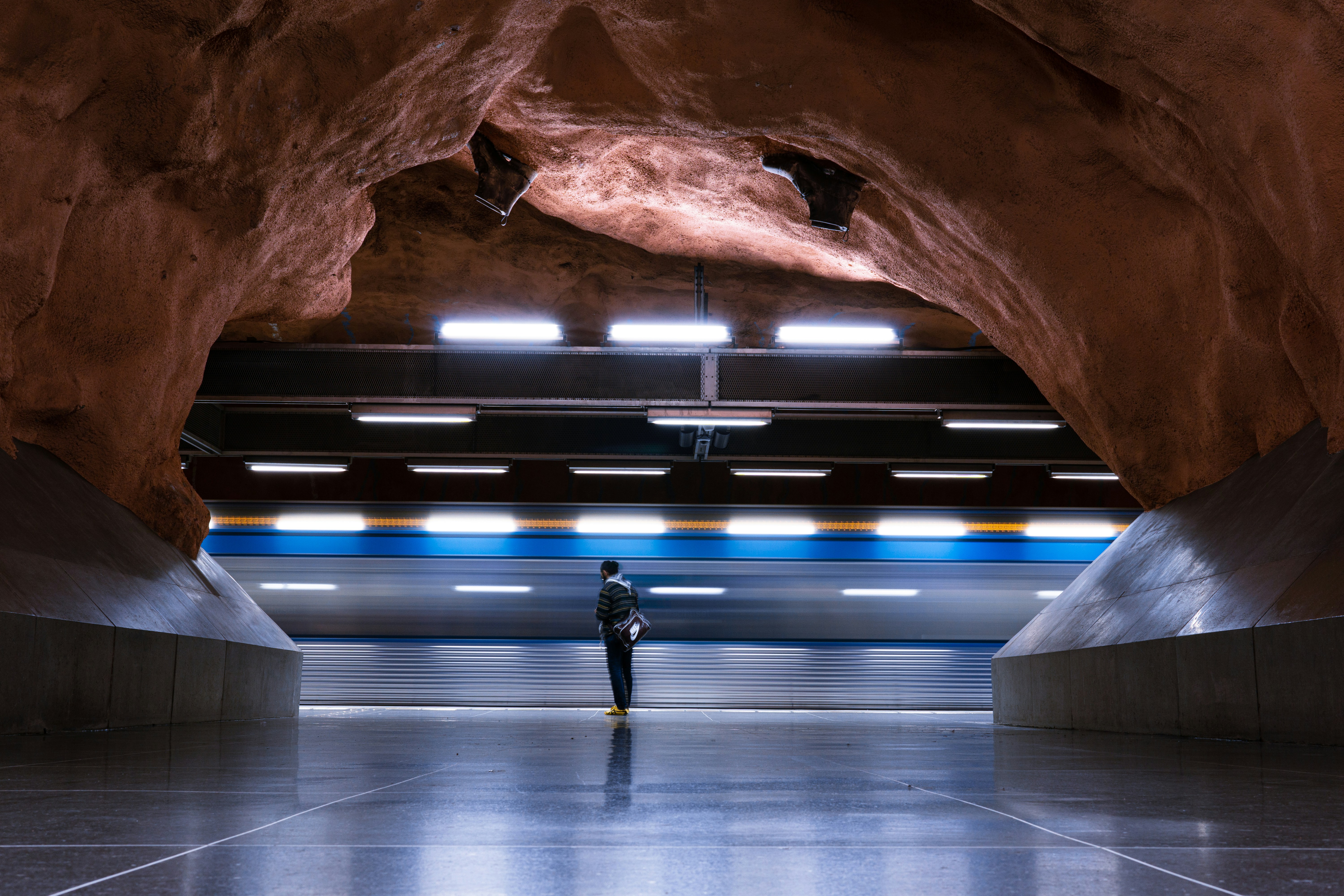a man standing in a tunnel between two large rocks