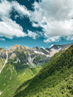 Sweeping mountain landscape showing the contrast between lush green valleys and rocky high-altitude terrain.