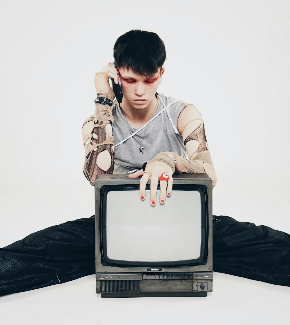 a man sitting on the floor with a tv in front of him