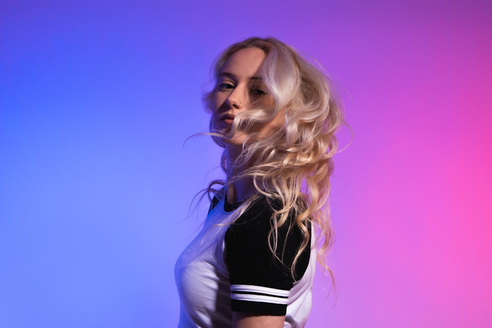 a woman with long blonde hair standing in front of a purple and blue background