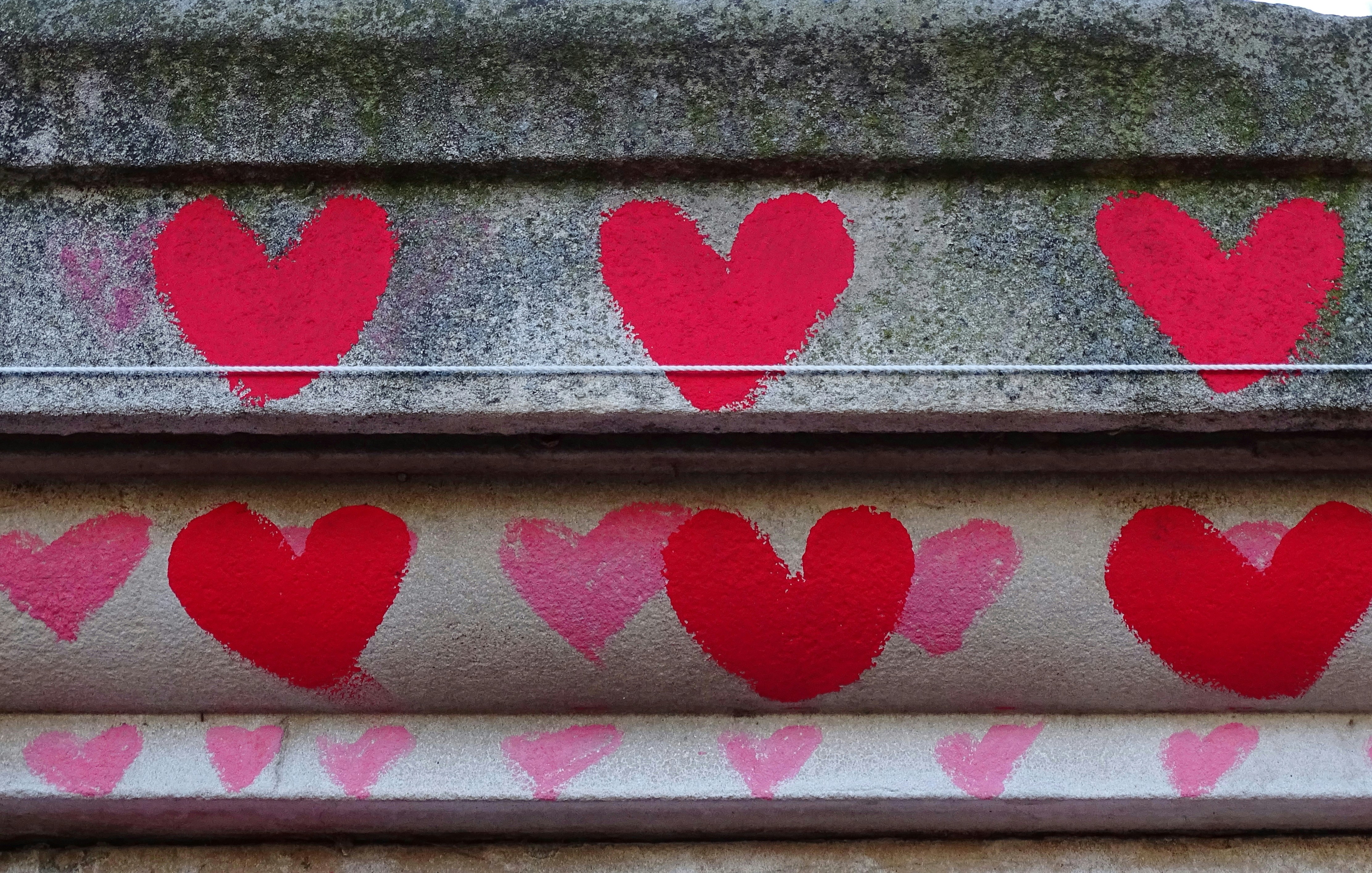 Red and pink hearts chalked or painted on a wall. These were not drawn in response to the Annunciation shooting.