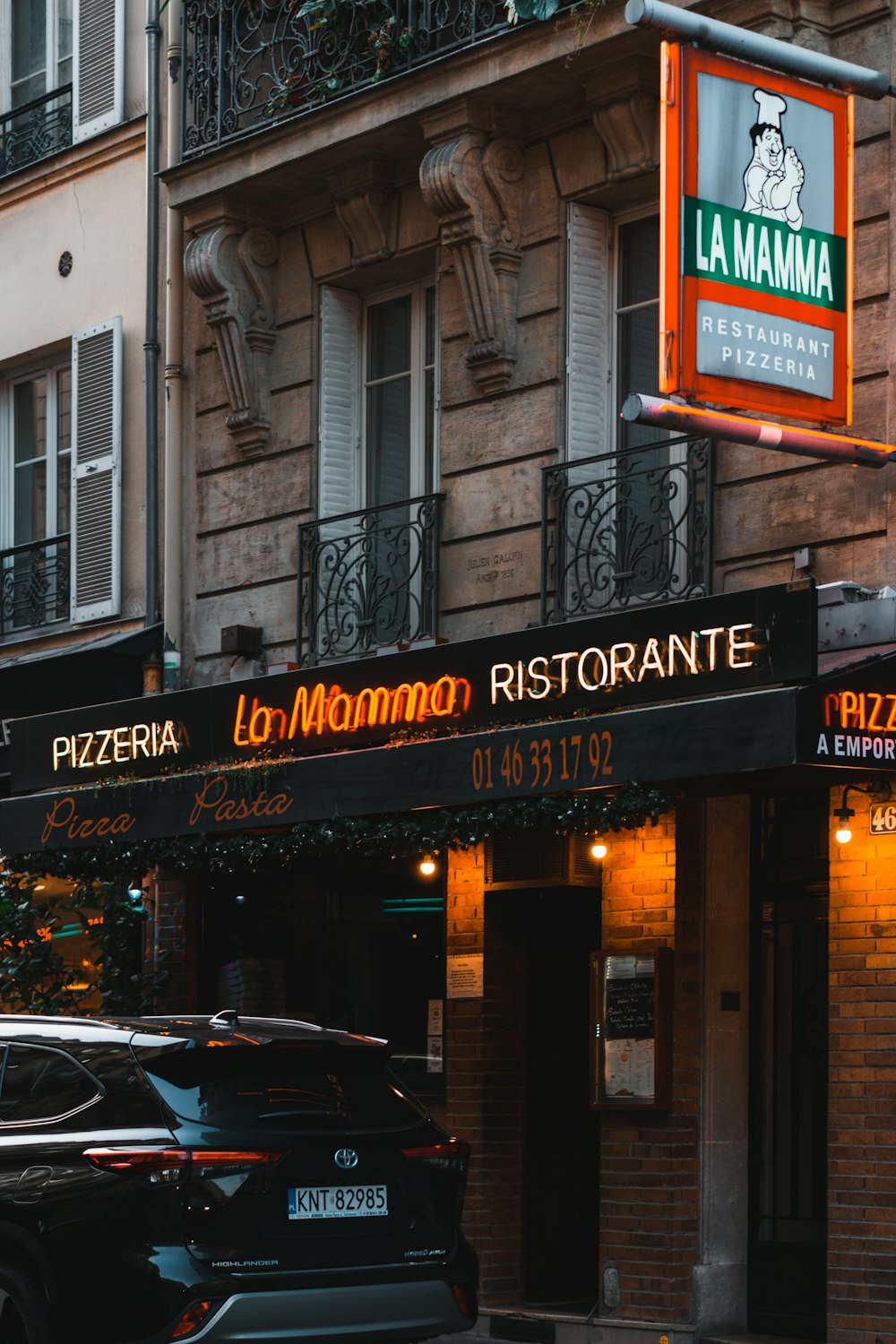 um carro preto estacionado em frente a um restaurante