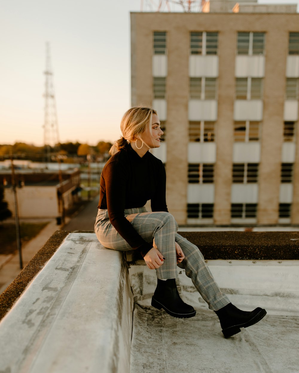 Une femme assise sur un rebord devant un immeuble