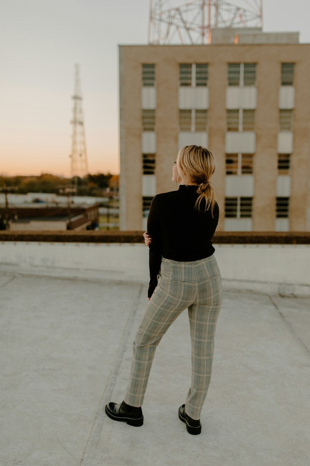 uma mulher de pé em um telhado com um edifício no fundo