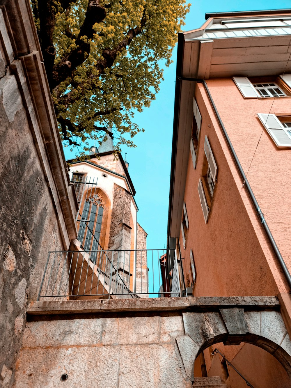 a tall building with a balcony next to a tree