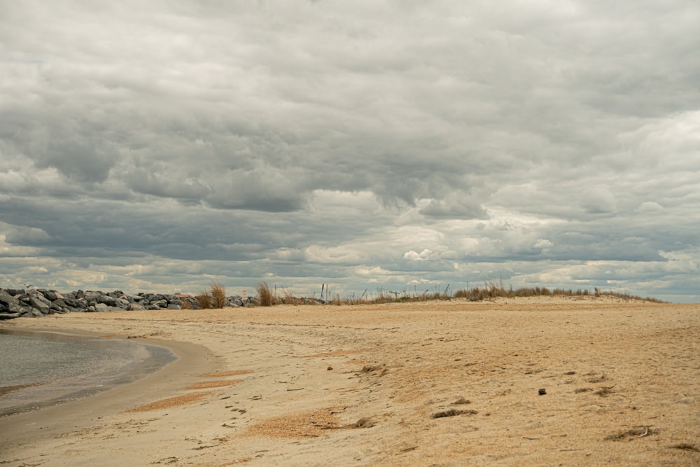 a sandy beach with a body of water under a cloudy sky