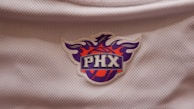 Detail shot of the phonix sun logo embroidered on the sleeve of a soft cotton hoodie.