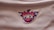 A logo set against a textured white fabric background, featuring a stylized phoenix above a basketball. The letters 'PHX' are prominently displayed in a bold font at the center.