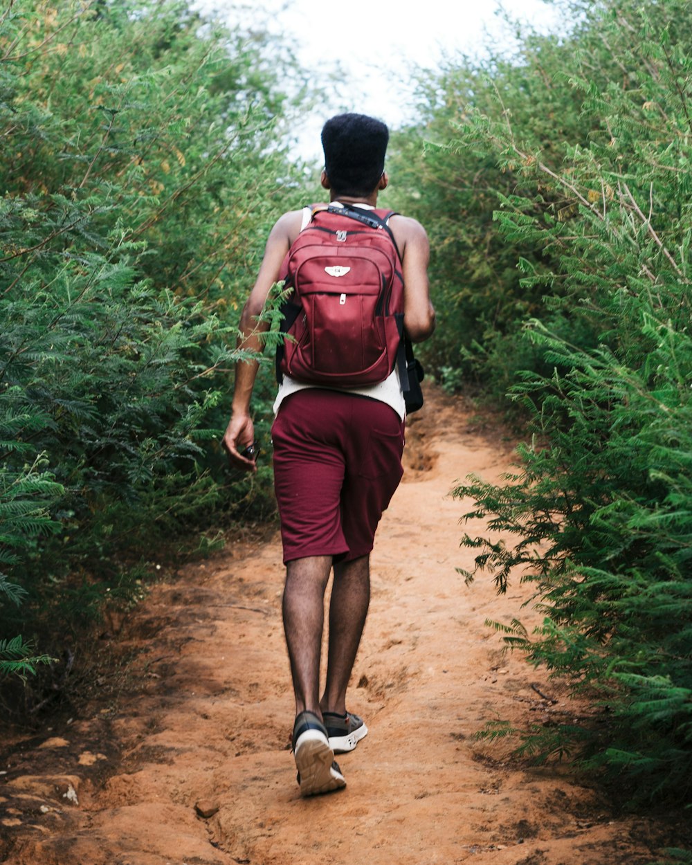 a man with a backpack walking down a dirt path