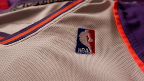 Close-up of a vibrant basketball jersey hanging on a rack, highlighting the fabric texture and stitching details.