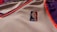 A close-up of a sports jersey made of mesh fabric features the NBA logo prominently. The jersey has an orange and purple trim on a white background.