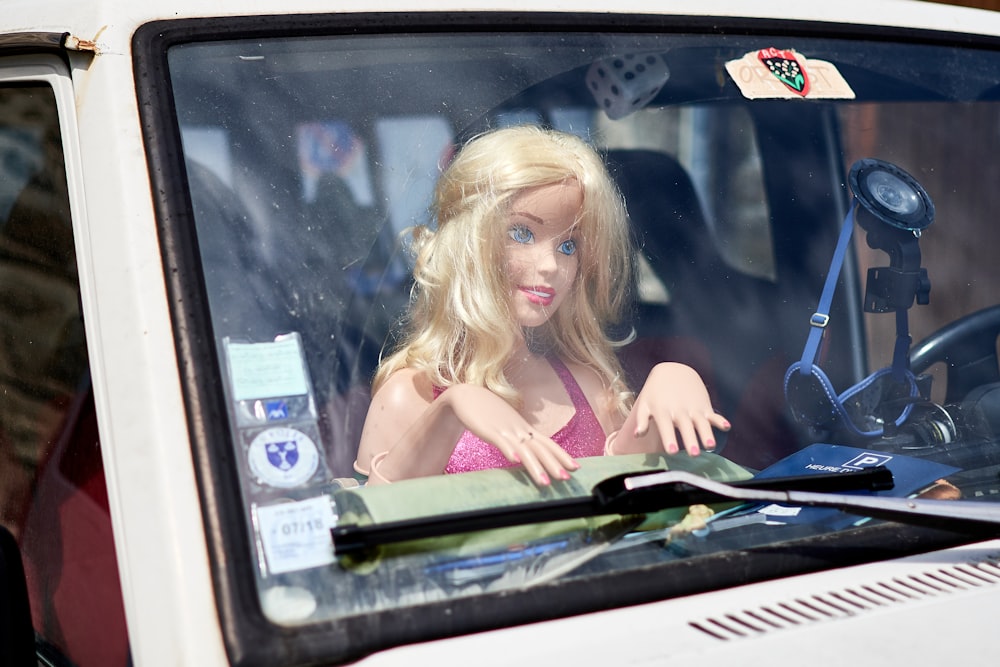 a barbie doll sitting in the drivers seat of a car