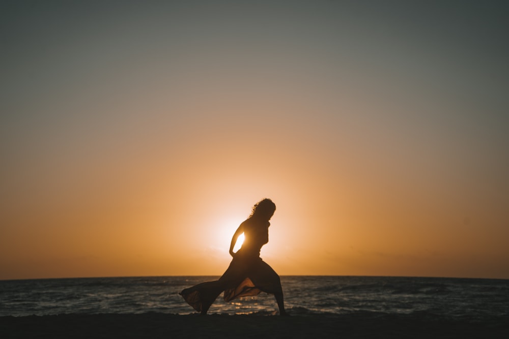 a woman standing on top of a beach next to the ocean