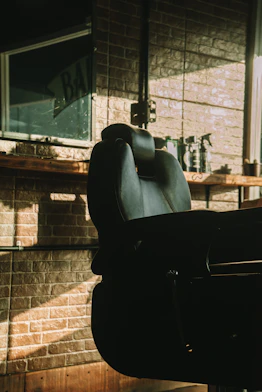 a black chair sitting in front of a brick wall